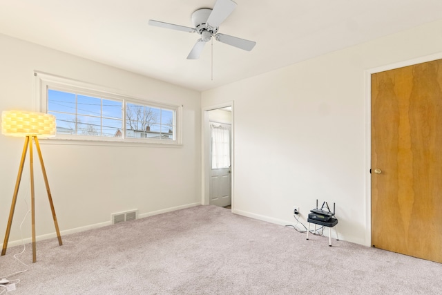 empty room featuring ceiling fan and light colored carpet