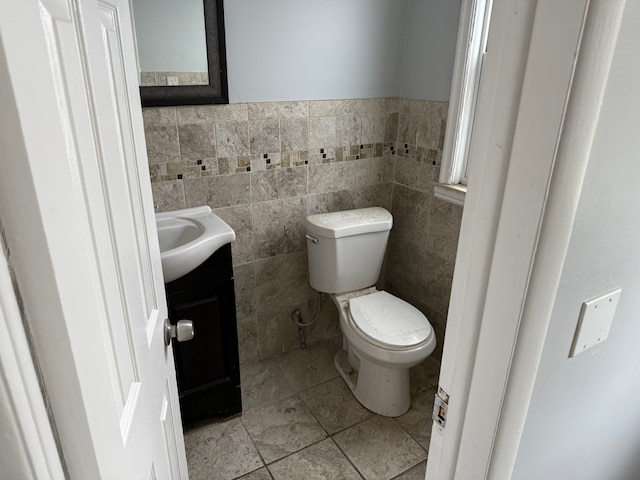 bathroom featuring vanity, toilet, and tile walls