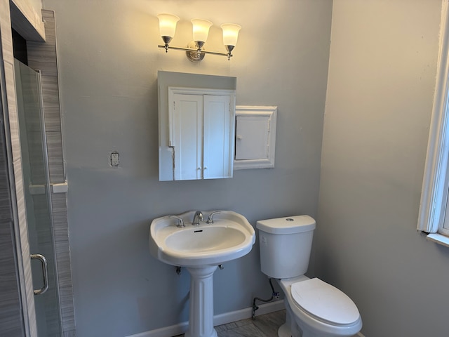 bathroom featuring a shower with door and toilet