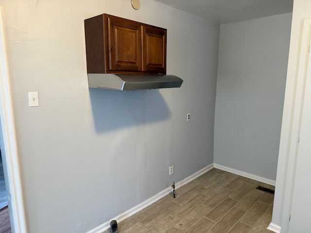 laundry area with cabinets, gas dryer hookup, and light hardwood / wood-style floors