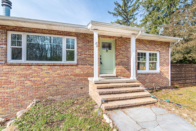 doorway to property with brick siding and fence