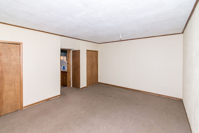 empty room with baseboards, crown molding, and carpet