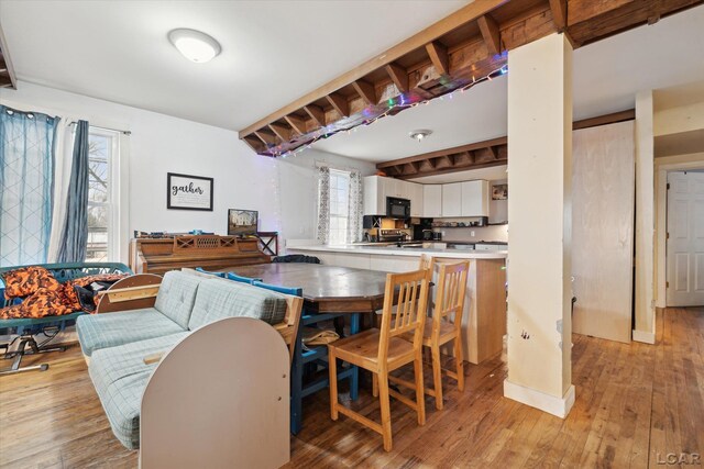 dining area with beam ceiling, light hardwood / wood-style floors, and a healthy amount of sunlight