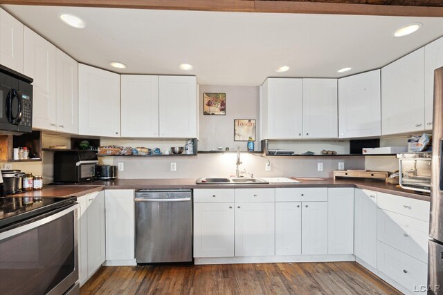 kitchen with white cabinetry, appliances with stainless steel finishes, sink, and dark hardwood / wood-style floors