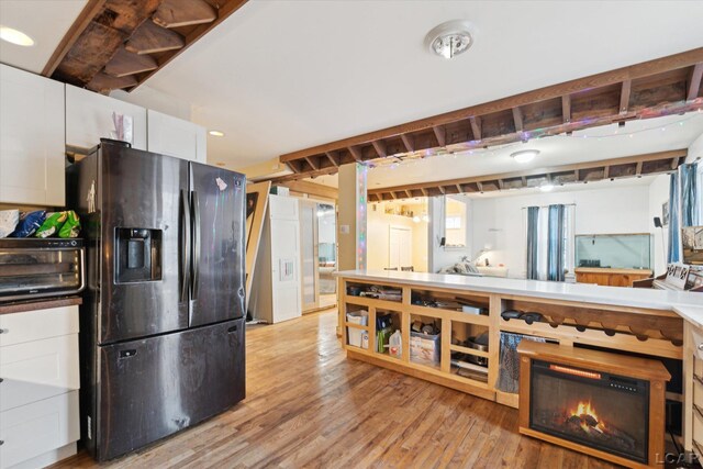 kitchen featuring stainless steel refrigerator with ice dispenser, white cabinets, and light wood-type flooring