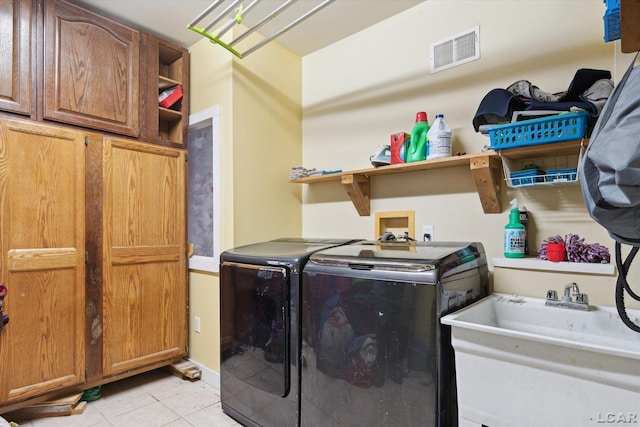 clothes washing area with separate washer and dryer, light tile patterned floors, sink, and cabinets