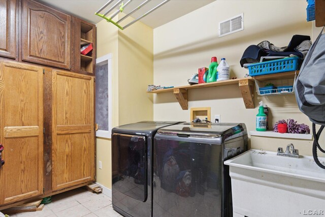 laundry room featuring separate washer and dryer, light tile patterned floors, sink, and cabinets