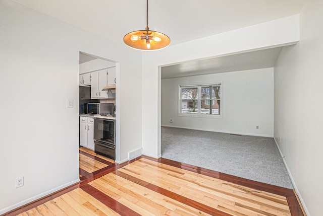 kitchen featuring white cabinetry, pendant lighting, range, and light hardwood / wood-style flooring