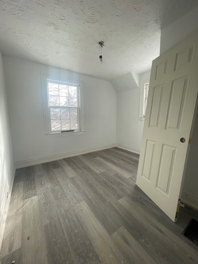 bonus room with lofted ceiling, dark hardwood / wood-style floors, and a textured ceiling