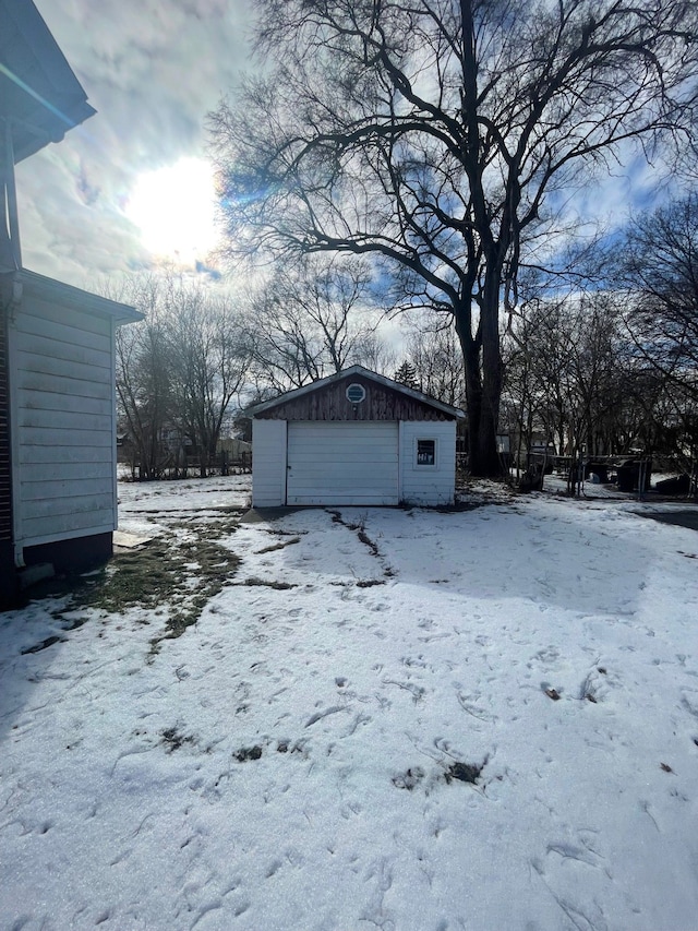 yard covered in snow featuring a garage and an outdoor structure