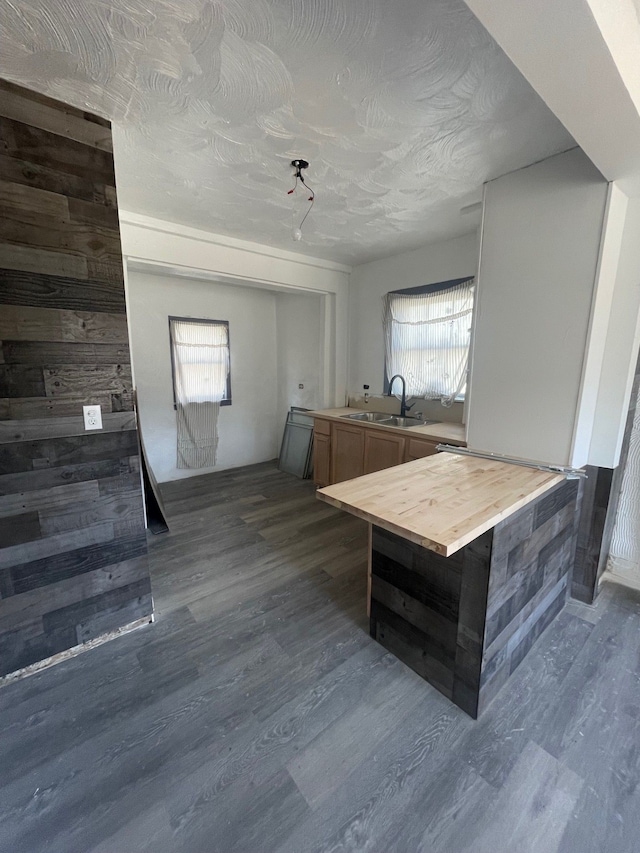 kitchen with wood walls, a sink, and wood finished floors
