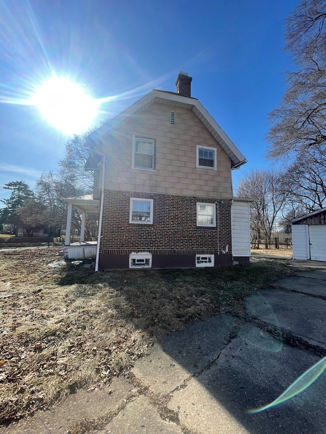 view of property exterior featuring brick siding and a chimney
