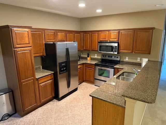 kitchen featuring appliances with stainless steel finishes, kitchen peninsula, sink, and stone counters