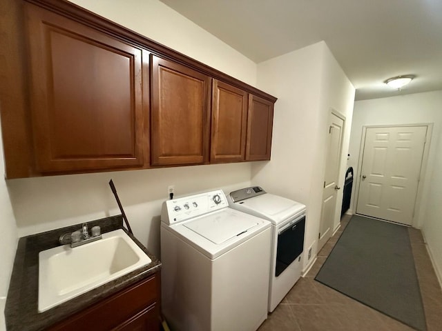 washroom with sink, washer and clothes dryer, cabinets, and dark tile patterned floors