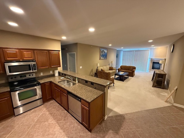 kitchen featuring light colored carpet, appliances with stainless steel finishes, kitchen peninsula, and sink