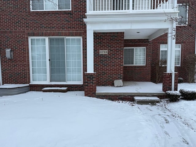 snow covered property entrance featuring a balcony