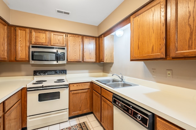 kitchen featuring a sink, light tile patterned flooring, visible vents, white appliances, and light countertops