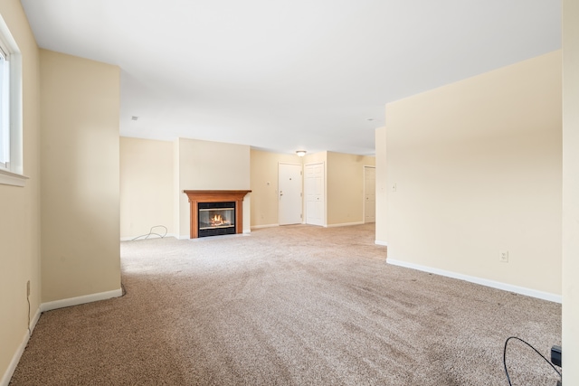 unfurnished living room featuring baseboards, a glass covered fireplace, and carpet floors