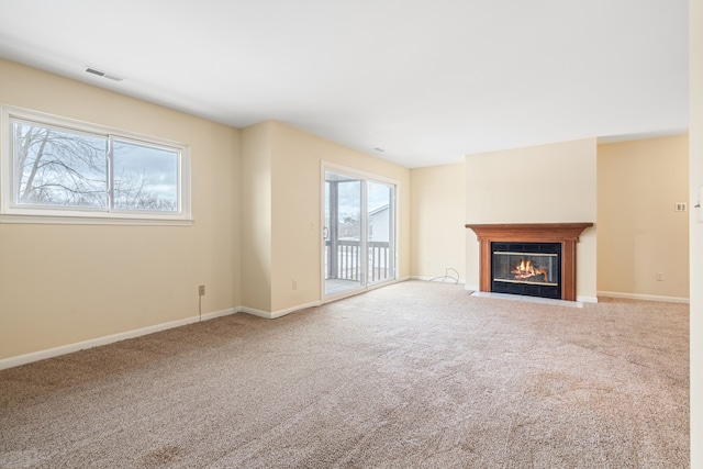 unfurnished living room with a fireplace with flush hearth, baseboards, visible vents, and carpet