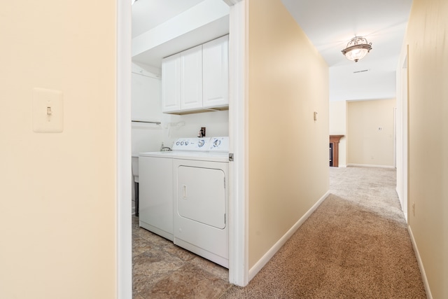laundry area featuring baseboards, washer and dryer, light colored carpet, and cabinet space