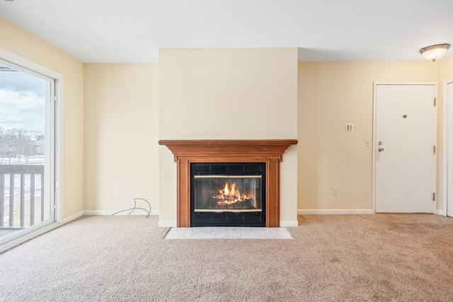 unfurnished living room featuring a fireplace with flush hearth, baseboards, a healthy amount of sunlight, and carpet flooring