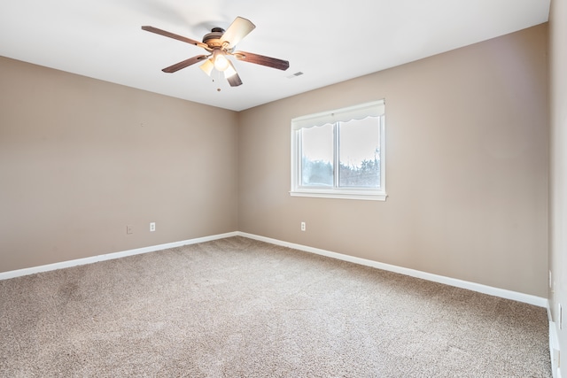carpeted empty room with baseboards, a ceiling fan, and visible vents