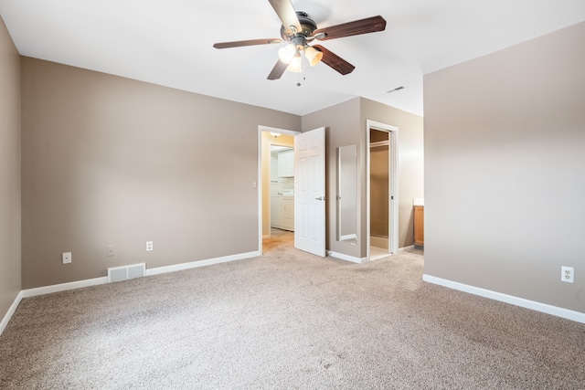 unfurnished bedroom featuring ceiling fan, light colored carpet, washer / clothes dryer, and a spacious closet