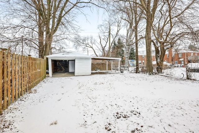 yard layered in snow with an outbuilding and a garage