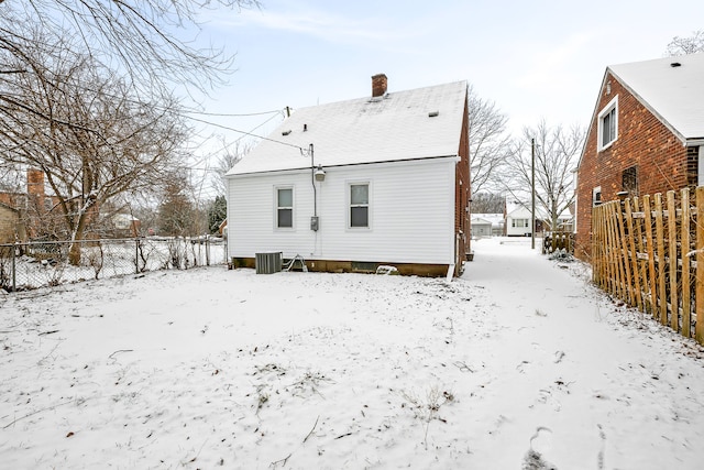 snow covered rear of property featuring central air condition unit