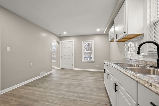 kitchen with sink, decorative backsplash, light hardwood / wood-style flooring, and white cabinets