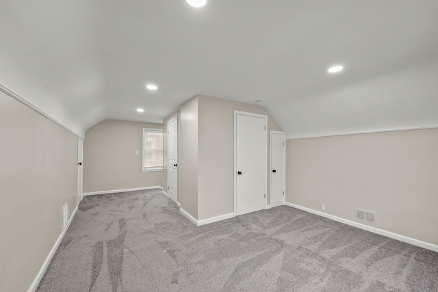 additional living space featuring lofted ceiling and light carpet