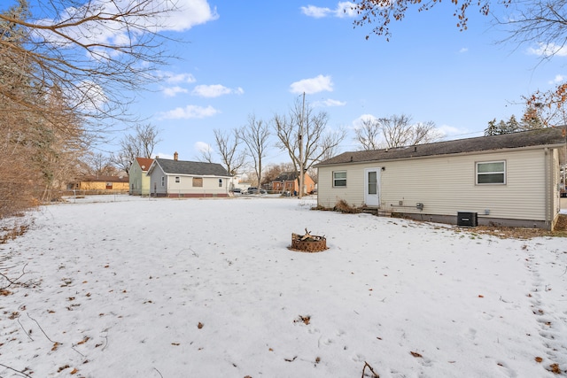 snow covered rear of property featuring a fire pit