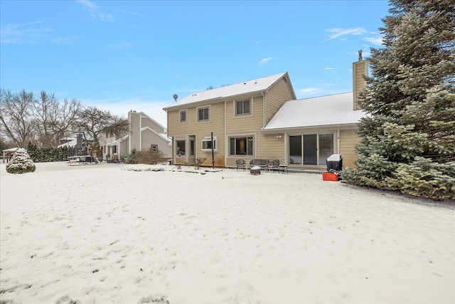 snow covered rear of property with an outdoor fire pit