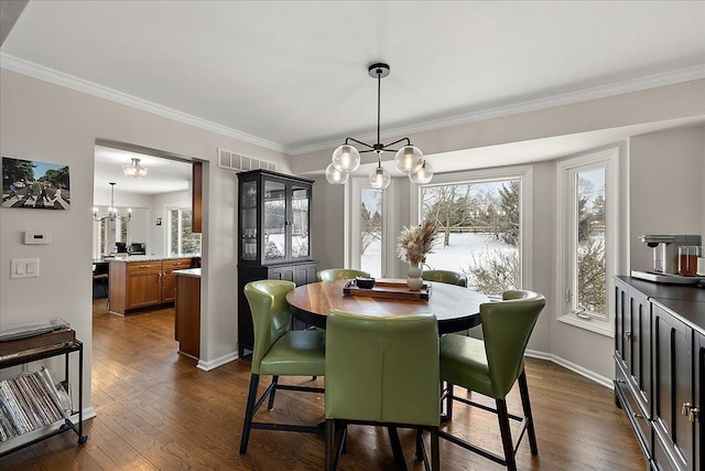 dining area with crown molding, dark wood-type flooring, and a chandelier