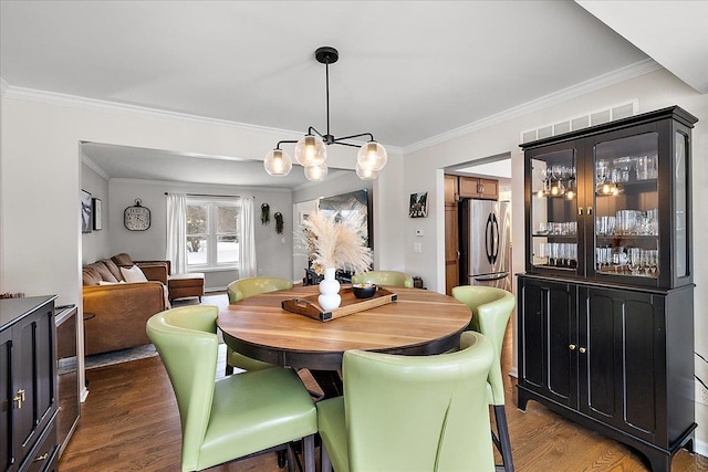 dining area featuring an inviting chandelier, dark wood-type flooring, and ornamental molding