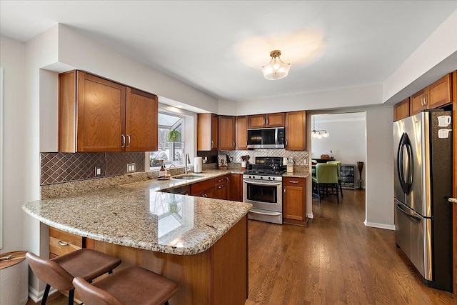 kitchen featuring sink, dark hardwood / wood-style floors, a kitchen breakfast bar, kitchen peninsula, and stainless steel appliances