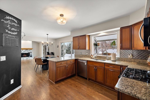 kitchen featuring sink, hanging light fixtures, appliances with stainless steel finishes, dark hardwood / wood-style floors, and kitchen peninsula