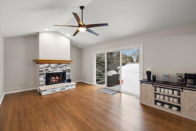 living room with lofted ceiling, a stone fireplace, wood-type flooring, and ceiling fan