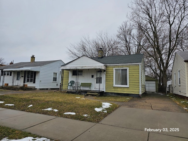 view of front of home with a garage, an outdoor structure, and a front yard