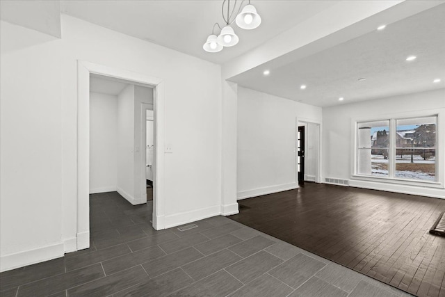 empty room featuring a chandelier and dark hardwood / wood-style flooring