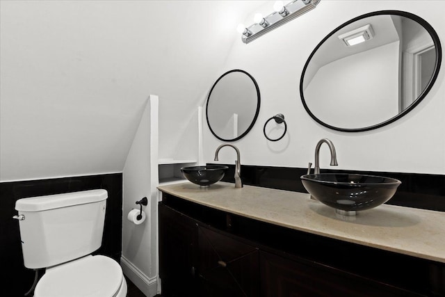 bathroom featuring lofted ceiling, vanity, and toilet