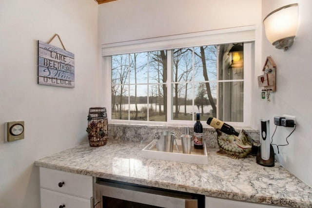 interior space with light stone countertops, beverage cooler, and white cabinets