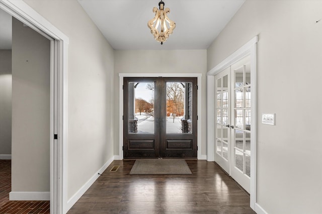 entryway with french doors, dark hardwood / wood-style floors, and an inviting chandelier