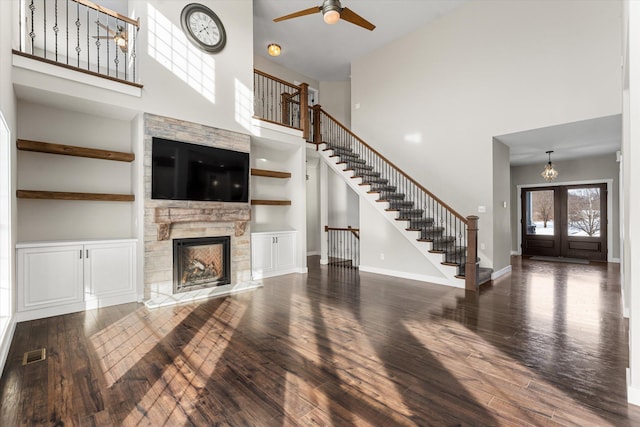 unfurnished living room featuring dark hardwood / wood-style floors, a fireplace, and a towering ceiling