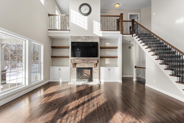 unfurnished living room with a fireplace, dark hardwood / wood-style floors, and a high ceiling