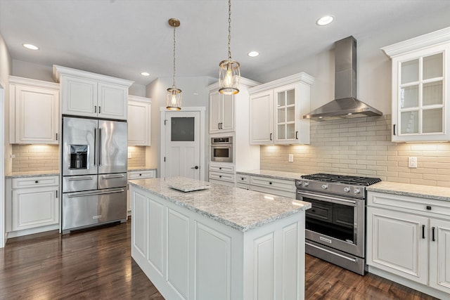 kitchen featuring white cabinetry, appliances with stainless steel finishes, a kitchen island, and wall chimney range hood