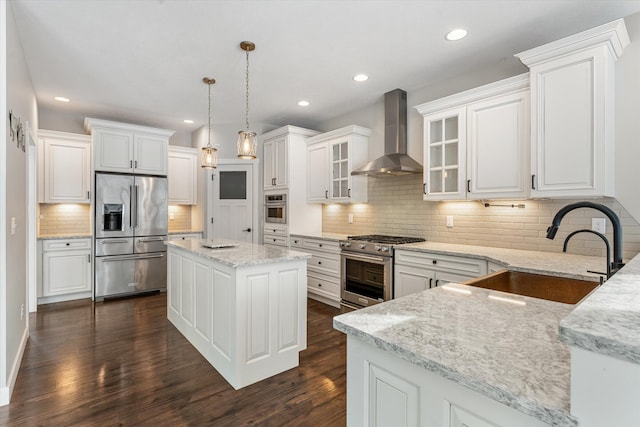 kitchen featuring a kitchen island, appliances with stainless steel finishes, sink, white cabinets, and wall chimney range hood