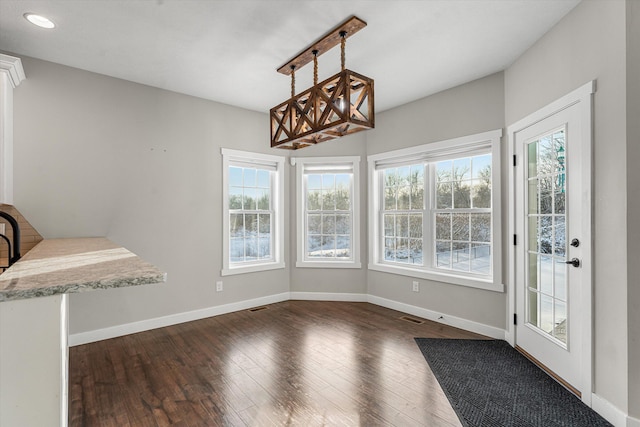 unfurnished dining area featuring a healthy amount of sunlight and dark wood-type flooring