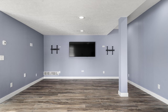 unfurnished living room featuring dark wood-type flooring and a textured ceiling