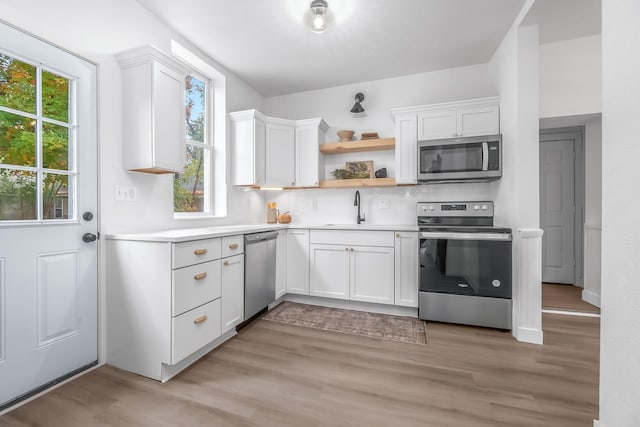 kitchen with white cabinetry, appliances with stainless steel finishes, light hardwood / wood-style floors, and sink